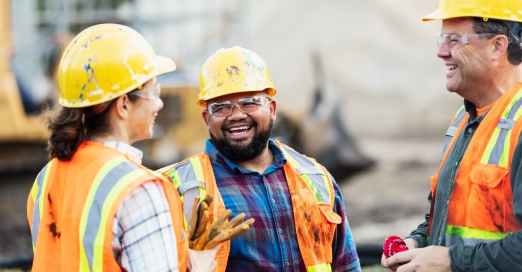 three construction workers of different generations talking on jobsite.