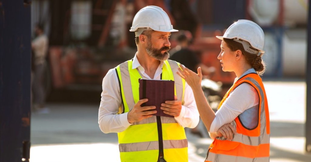 two construction workers on jobsite discussing design problems.