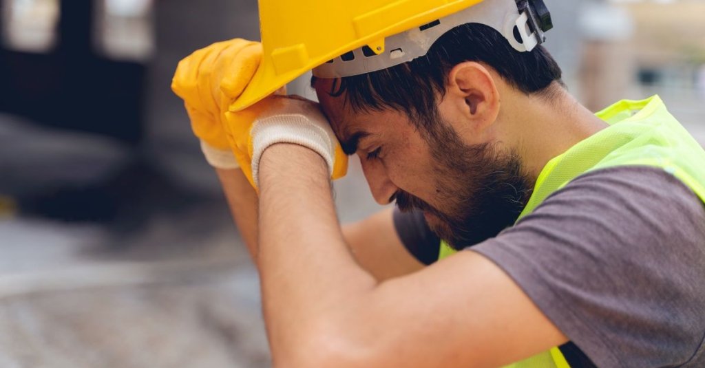 construction worker wiping forehead.