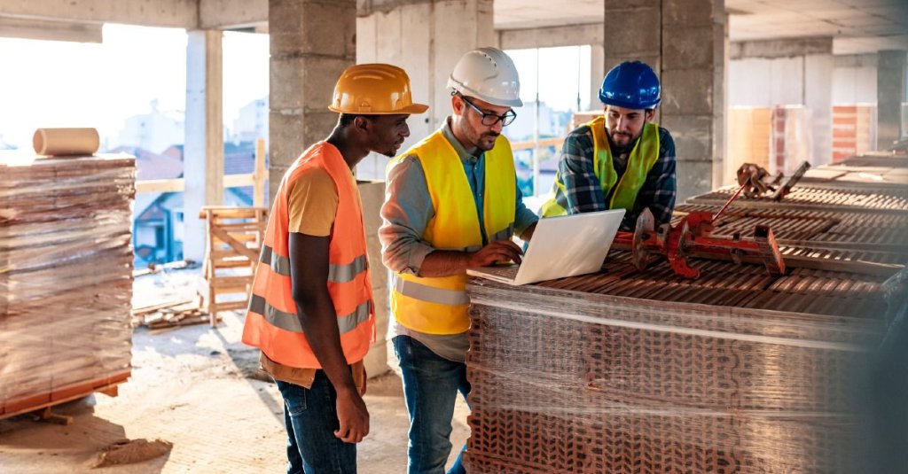 construction workers using laptop on jobsite.