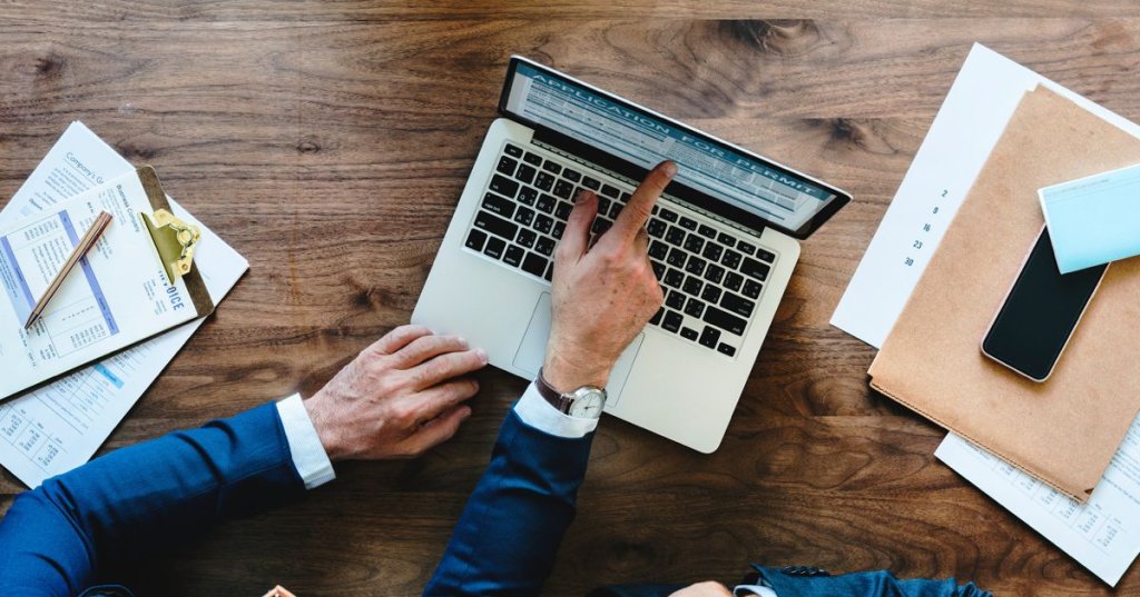 person pointing at something on laptop screen.