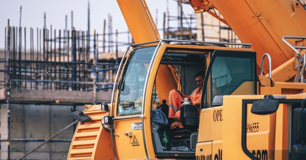 construction worker sitting in excavator on jobsite.