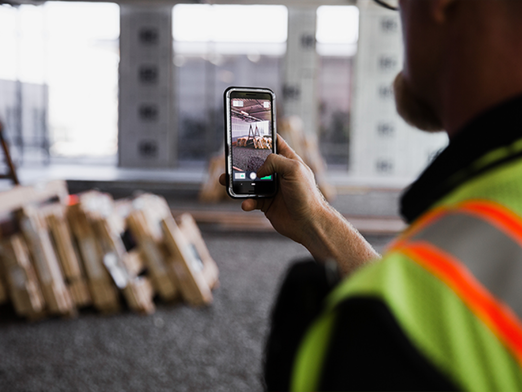 Construction worker using construction photo app on jobsite.