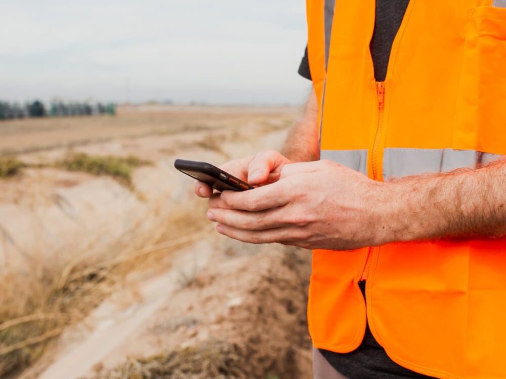 Contractor using phone in field.