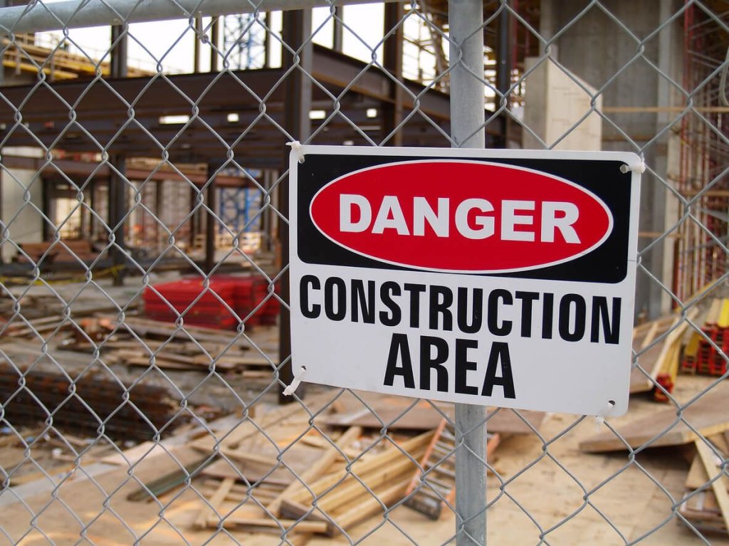 Danger warning sign on construction site fence.
