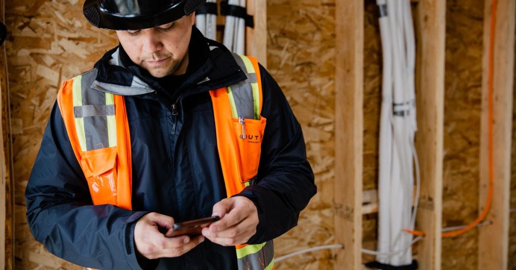 construction worker creating daily report on mobile phone on jobsite.