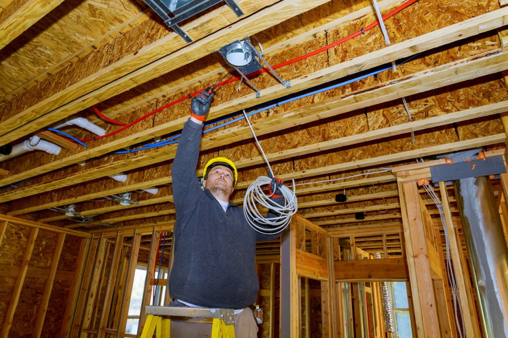 worker running electrical wire on construction site.