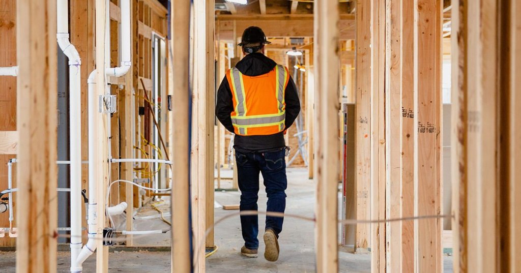 Construction worker walking through half-constructed building.