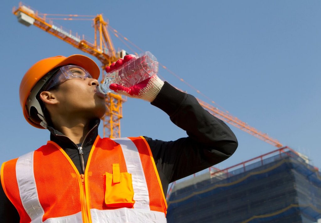 Construction worker drinking water to stay hydrated on jobsite.