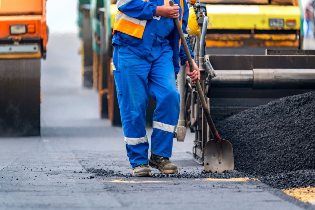 Construction worker working in heat on road.