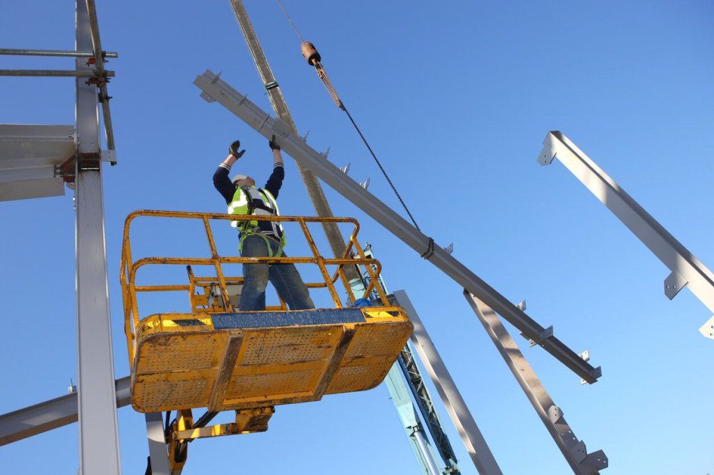 construction worker crane lifting and rigging a steel beam.