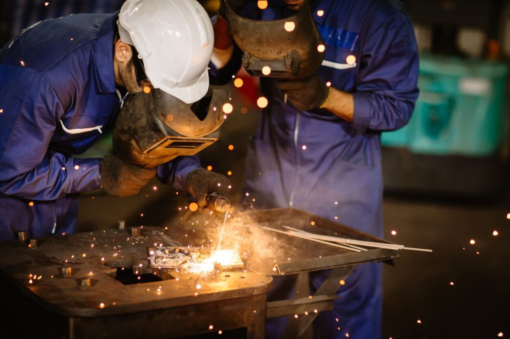 two workers welding metal.