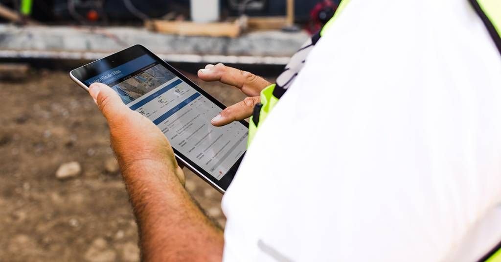 contractor filling out daily report on iPad in field.