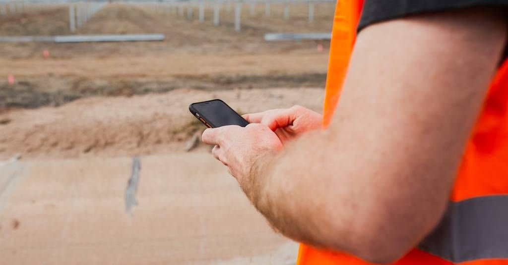 construction worker using construction time card app in field.