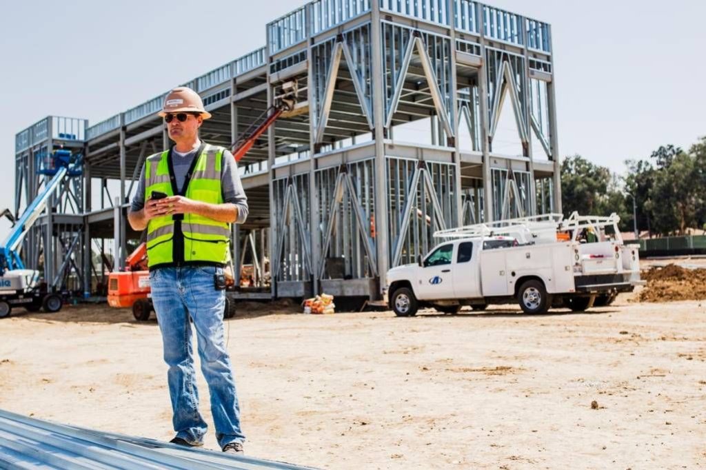 construction worker filling out mobile time card in field.