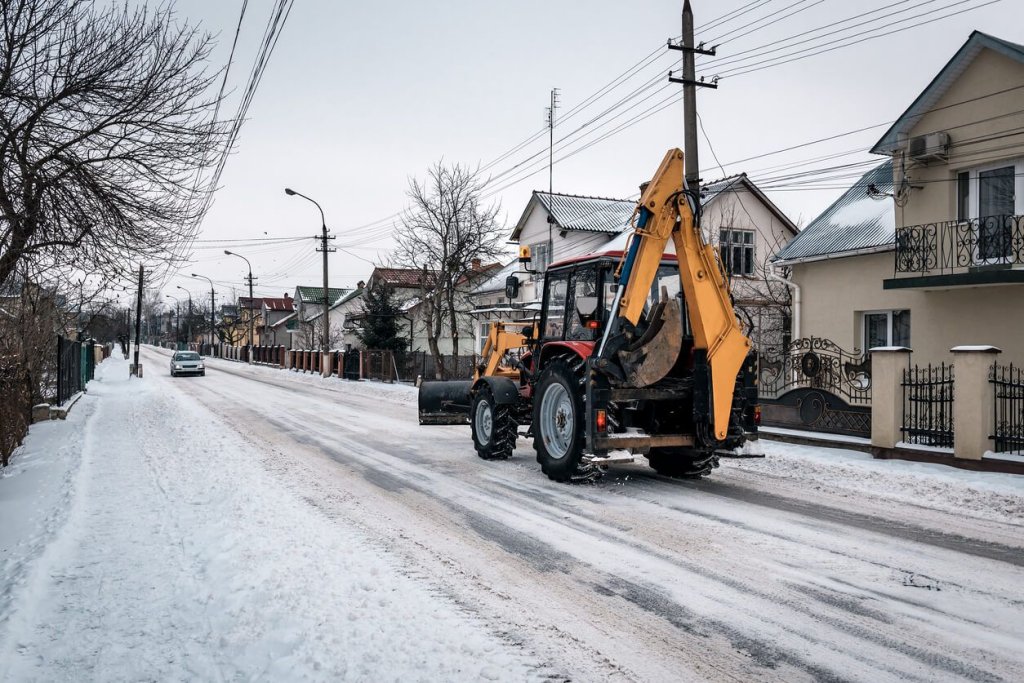 Construction worker driving tractor in the snow during winter.